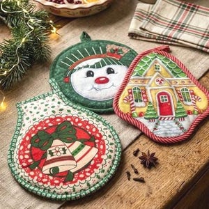 May include: Three fabric pot holders featuring holiday designs: one round holder with a snowman face, one bell-shaped holder with a yellow house and candy cane accents, and one bell-shaped holder with a red circle and two white bells with a green bow.