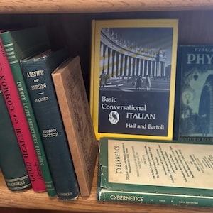 May include: A bookshelf with a variety of books, including "Good Health and Common Sense", "A Review of Nursing", "Basic Conversational Italian", and "Visualized Physics".