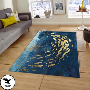 Puede incluir: Una alfombra azul y dorada con un dise&ntilde;o de un banco de peces nadando en un patr&oacute;n circular. La alfombra tiene un fondo desgastado, como una acuarela.
