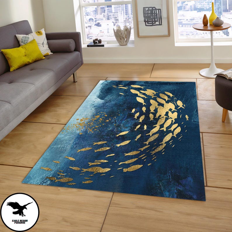 Puede incluir: Una alfombra azul y dorada con un dise&ntilde;o de un banco de peces nadando en un patr&oacute;n circular. La alfombra tiene un fondo desgastado, como una acuarela.
