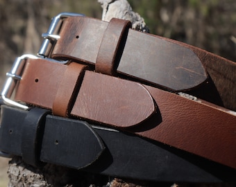 May include: Three leather belts with silver buckles. The belts are stacked on top of each other. The top belt is brown, the middle belt is dark brown, and the bottom belt is black.