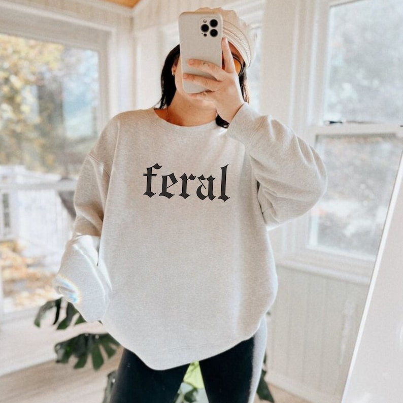 May include: A gray sweatshirt with the word "feral" printed in black gothic lettering.