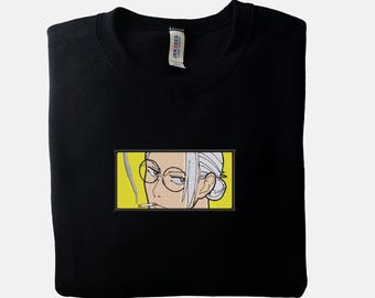 May include: Black sweatshirt with a rectangular embroidered patch featuring an anime-style illustration of a person with glasses smoking a cigarette. The patch has a yellow background.