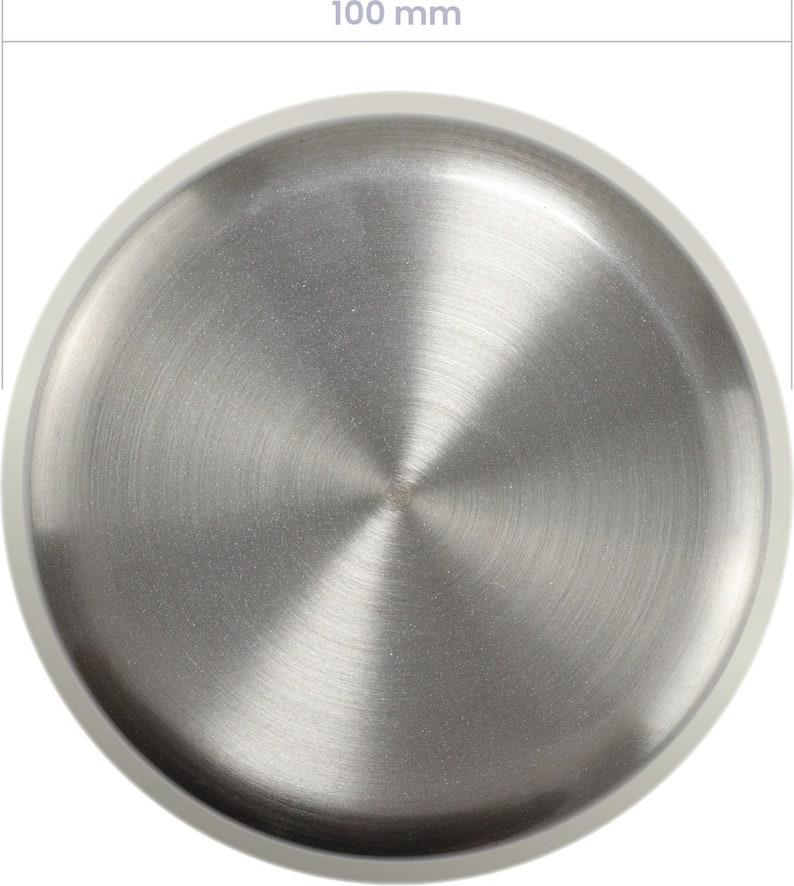 May include: A circular, brushed stainless steel object with a diameter of 3.9 inches. The metal surface has a radial grain pattern, and a white border surrounds the edge. The object is likely a lid or a small plate.