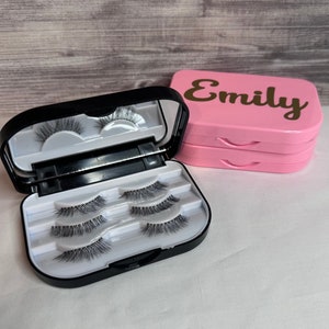May include: A black lash case with a mirror and three compartments for storing false eyelashes. The case is open and the lashes are visible. A pink case with the name "Emily" on it is also shown.