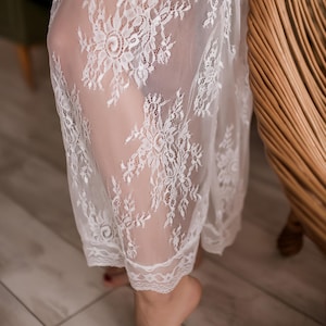 Puede incluir: Batista blanca de encaje con un delicado patr&oacute;n floral. La bata es transparente y tiene un borde festoneado.