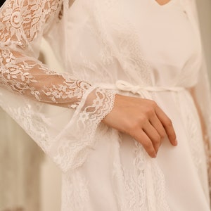 May include: White lace robe with long sleeves and a tie at the waist.