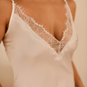May include: A white satin camisole with a lace trim neckline.