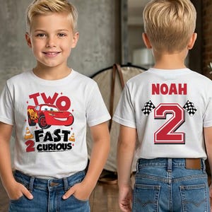Op de afbeelding: Witte T-shirts met een rood-zwart grafisch ontwerp. De voorkant van het shirt zegt "TWO FAST 2 CURIOUS" met een rode raceauto. De achterkant van het shirt zegt "NOAH" en het nummer "2" met geblokte vlaggen.