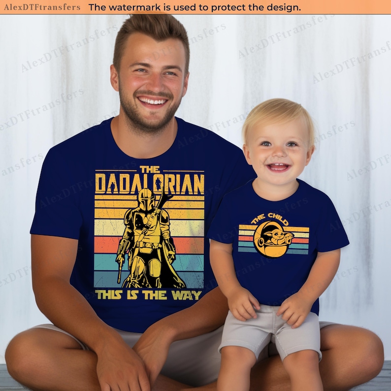 K&ouml;nnte beinhalten: Marineblaue T-Shirts mit passenden Designs. Ein Shirt tr&auml;gt "THE DADALORIAN" mit einer Mandalorianer-Grafik, das andere "THE CHILD" mit einer Grogu-Grafik. Der Text "THIS IS THE WAY" steht ebenfalls auf dem ersten Shirt.