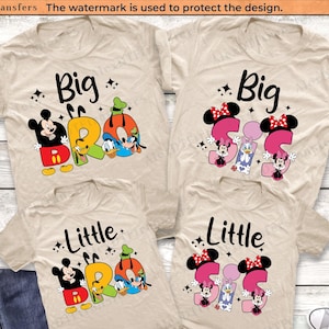 以下が含まれることがあります： 「Big Bro」と「Little Bro」の文字が黒字で書かれたベージュ色のTシャツ。ミッキーマウス、ドナルドダック、グーフィーのグラフィックが特徴です。他のシャツには、ミニーマウスとデイジーダックのグラフィックで「Big Sis」と「Little Sis」と書かれています。