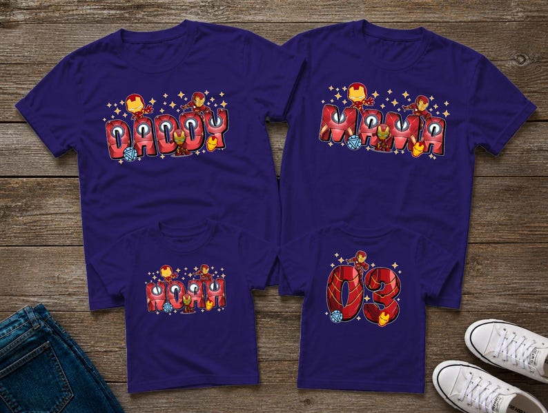May include: Four matching navy blue t-shirts with Iron Man-themed designs. Two adult shirts say "Daddy" and "Mama" in red bubble letters. The other two shirts say "03" and "Mini" in red bubble letters. All shirts have Iron Man graphics.