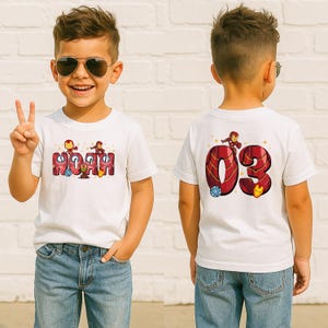 May include: White t-shirt featuring the name "Noah" in a red and gold Iron Man-themed design on the front. The back of the shirt displays the number "03" with Iron Man graphics. The shirt is worn by a child.