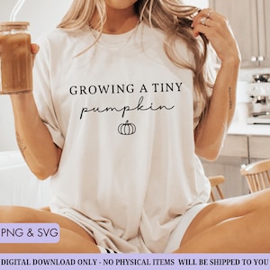 May include: A white t-shirt with the text "GROWING A TINY pumpkin" in black script and a small pumpkin graphic. The shirt is a digital download, available in PNG and SVG formats.