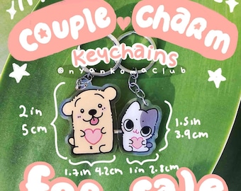 Puede incluir: Dos llaveros magnéticos de pareja con un perro y un gato de dibujos animados, cada uno con un corazón rosa. El llavero del perro mide 5 cm de alto y el llavero del gato mide 3,9 cm de alto. Se muestra el texto "Couple Charm Keychains".