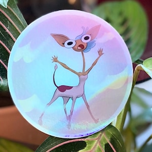 Könnte beinhalten: Ein runder Aufkleber mit einer Cartoonfigur. Die Figur hat einen langen Hals, große Augen und ausgestreckte Arme. Der Aufkleber hat einen holografischen Effekt mit rosa, blauen und gelben Farbtönen. Der Hintergrund ist eine Pflanze mit grünen Blättern.