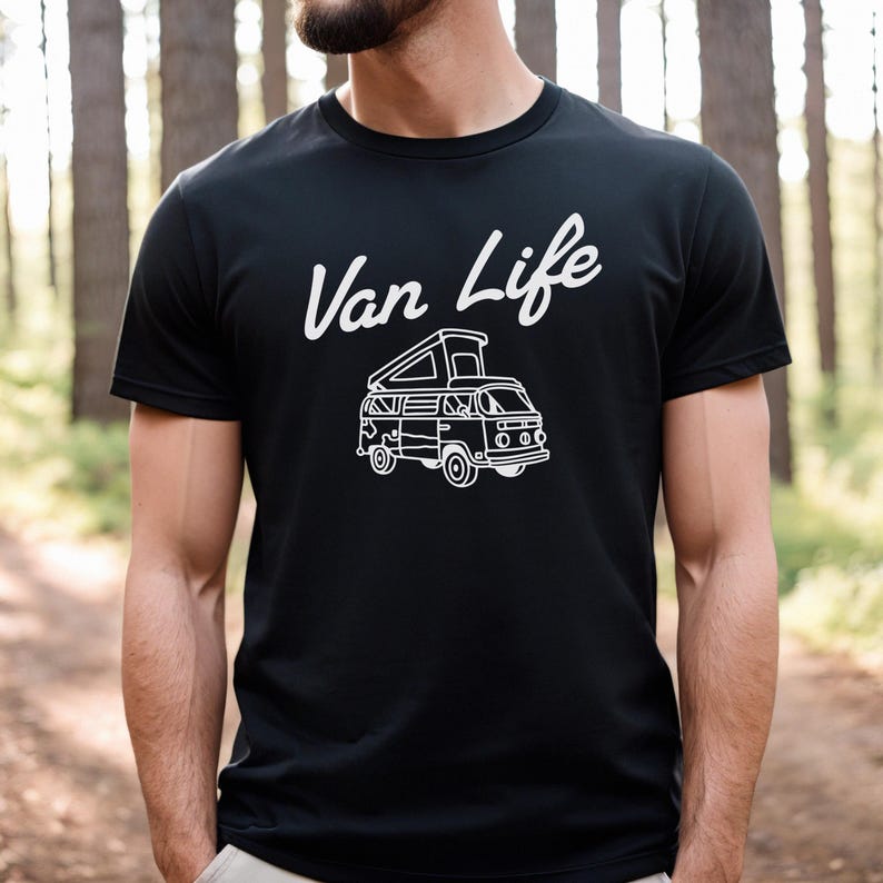 May include: Black t-shirt with the white text "Van Life" above a white illustration of a camper van. The camper van has an open top and is facing forward. The shirt is short-sleeved.