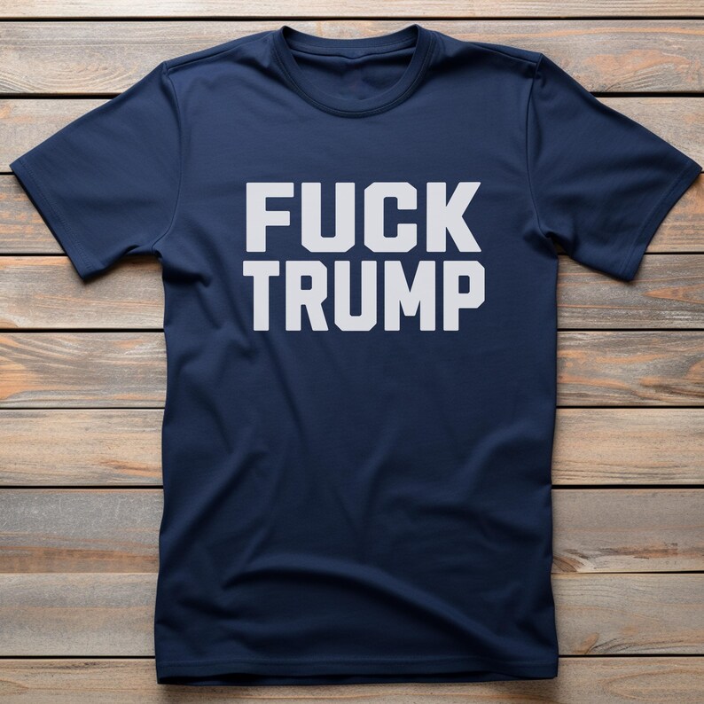 May include: A navy blue t-shirt with the text "FUCK TRUMP" printed in white.