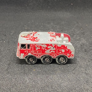 May include: A red and silver toy truck with a crane arm. The truck has four wheels and is made of metal. The truck is in a slightly worn condition.