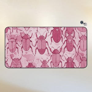 May include: Pink and white mousepad with a repeating pattern of pink beetles. The beetles are drawn in a simple, cartoon style.