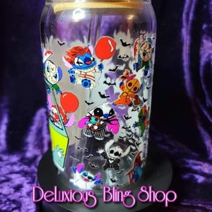 May include: A clear glass jar with a wooden lid and a straw. The jar is decorated with cartoon characters from the film "Lilo & Stitch" dressed in Halloween costumes. The jar is sitting on a black base with the text "Deluxious Bling Shop".
