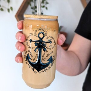 May include: A brown and beige reusable coffee cup with a bamboo lid and a blue anchor graphic. The anchor has a white bow and is surrounded by text that reads "We have this as a sure and steadfast anchor of the soul that we may enter into the inner place. Hebrews 6:18-19. We who have fled for refuge might have strong encouragement to hold fast to the hope set before us."