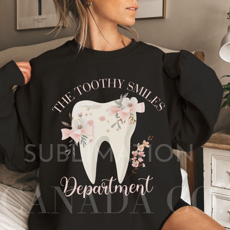 May include: Black sweatshirt with a white tooth graphic and pink floral accents. The text "The Toothy Smiles Department" is printed on the sweatshirt.