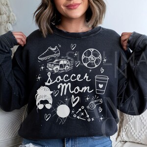 May include: Black sweatshirt with a white graphic design featuring a soccer ball, car, coffee cup, and the text "Soccer Mom".