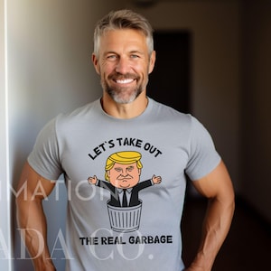 May include: A gray t-shirt with a cartoon image of a person in a trash can. The text on the shirt reads "Let's Take Out The Real Garbage".
