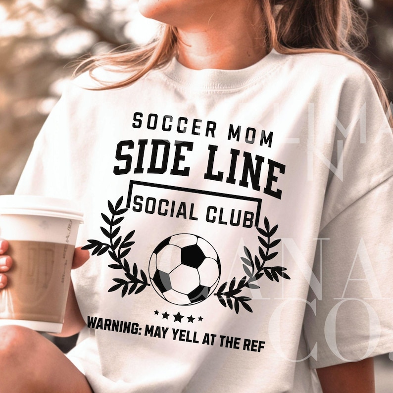 Puede incluir: Camiseta blanca con texto negro que dice "Soccer Mom Side Line Social Club" y un gr&aacute;fico de bal&oacute;n de f&uacute;tbol. El texto debajo del gr&aacute;fico dice "Advertencia: Puede gritarle al &aacute;rbitro."