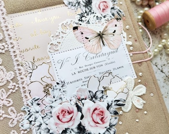 Puede incluir: Un diario beige con adornos florales y de mariposas. El diario presenta rosas rosas, una mariposa y encaje decorativo. El texto "I love you" es visible. Perlas y carretes de hilo rosa están en el fondo.