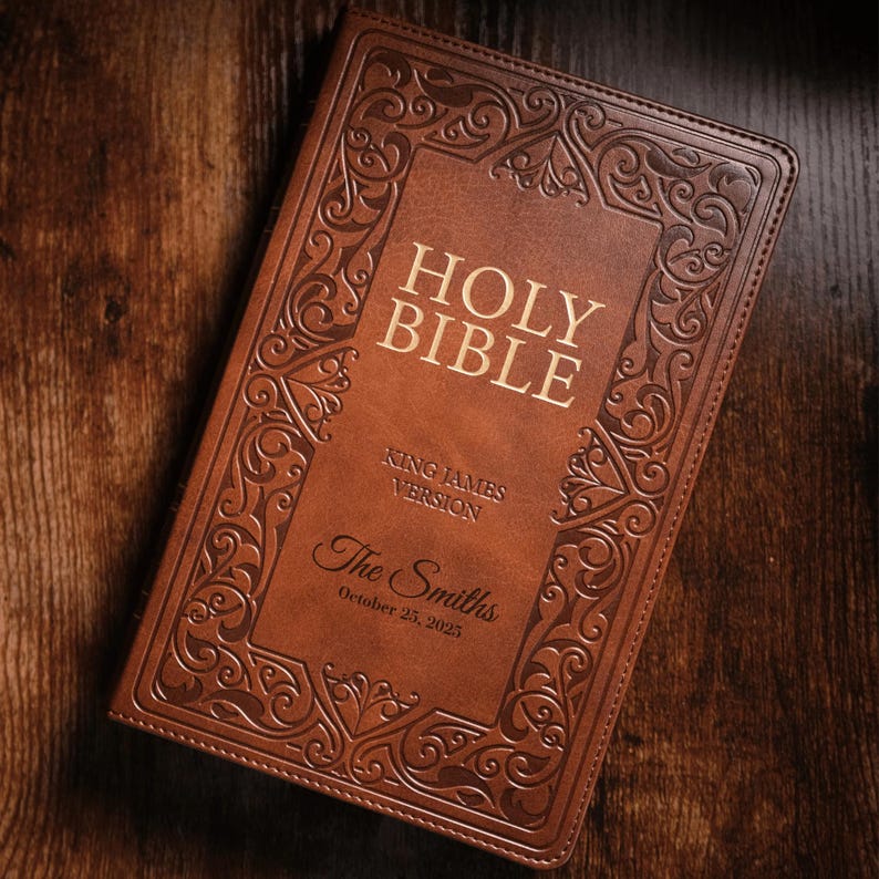 May include: A brown leather Holy Bible, King James Version, with decorative embossed detailing. The cover features the title "Holy Bible" in gold lettering, along with the names "The Smiths" and the date "October 25, 2025".