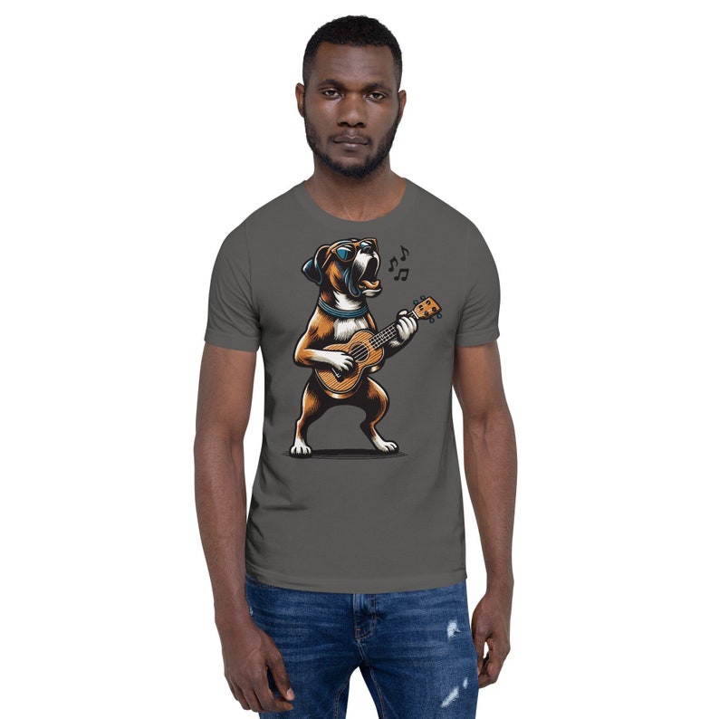 May include: Dark gray t-shirt featuring a cartoon Boxer dog playing a ukulele and singing. The dog is brown and white, wearing sunglasses and a blue collar. Musical notes float above the dog. The shirt is a short-sleeve style.