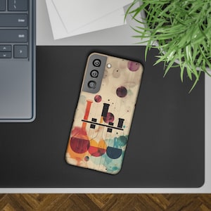 Op de afbeelding: Een smartphonehoesje met een kleurrijk abstract ontwerp van laboratoriumglaswerk. De hoes heeft een beige achtergrond met rode, oranje, gele en blauwe vormen. De telefoonhoes ligt op een zwart oppervlak.