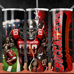 Puede incluir: Un vaso de acero inoxidable rojo y negro con un jugador de fútbol con cara de calavera que lleva una camiseta de los Buccaneers y sostiene un balón de fútbol. El vaso tiene un diseño rojo y negro con la palabra "Buccaneers" en letras blancas.