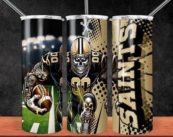 Puede incluir: Un vaso de acero inoxidable con un diseño negro y dorado que presenta a un jugador de fútbol con cara de calavera vistiendo una camiseta de los Saints. El vaso tiene una tapa negra y una pajita.