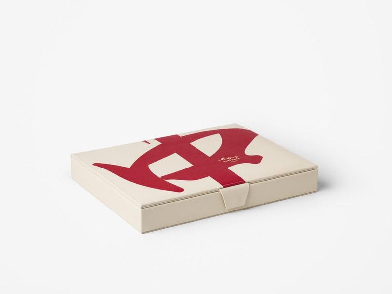 Puede incluir: Caja rectangular blanquecina con un gran dise&ntilde;o abstracto rojo en la tapa. La caja tiene un peque&ntilde;o cierre de broche. El texto "Maligry" est&aacute; impreso en la tapa. Un elemento gr&aacute;fico llamativo.
