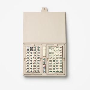 Puede incluir: Un juego de Mahjong beige abierto, que revela fichas y dados. Las fichas est&aacute;n en dos compartimentos dentro de un estuche beige a juego. Las fichas muestran s&iacute;mbolos y caracteres en verde, rojo y negro. El estuche es rectangular.