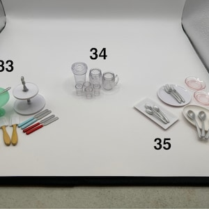 Pode incluir: Uma coleção de acessórios de cozinha e jantar em miniatura. Inclui um suporte de serviço em camadas, pratos, utensílios, facas, xícaras e travessas. Os itens são em várias cores, incluindo branco, transparente, vermelho, azul, amarelo e verde.