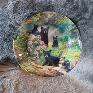 May include: A glass plate with a black bear family design. The bears are surrounded by green foliage and pink flowers. The plate is perfect for serving snacks or desserts.