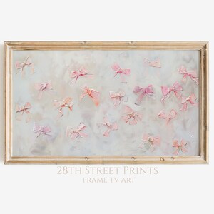 May include: A framed painting of a light grey background with pink bows scattered across the surface. The frame is a light wood colour.