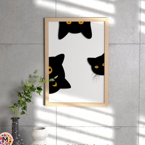 May include: A framed art print featuring a minimalist design of three black cat faces with yellow eyes peeking out from behind a white background. The artwork is in a light wood frame, displayed against a gray concrete wall.