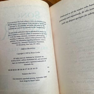 May include: Open book pages with text. The left page contains copyright information, ISBN, and publisher details. The right page has a dedication. The book is a paperback, printed in the USA.