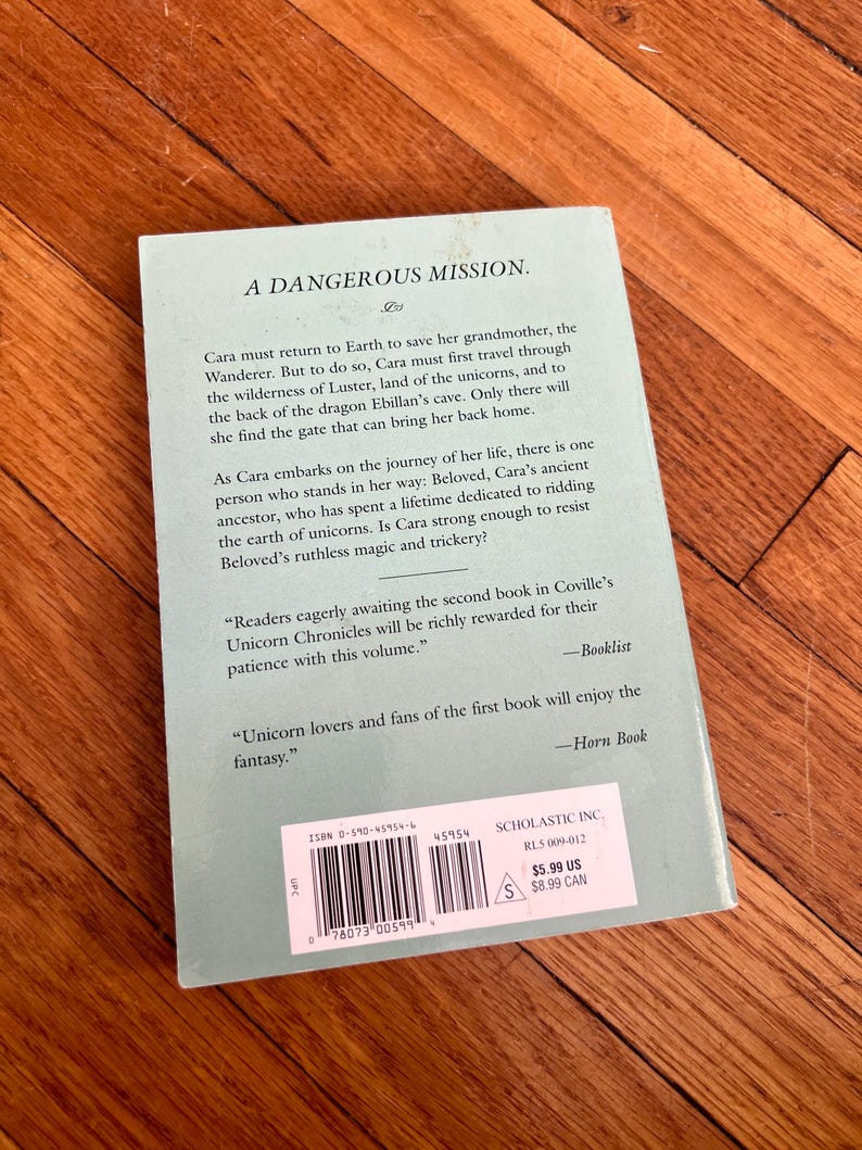 May include: A paperback book titled "A Dangerous Mission" with text on the back cover. The cover is a light teal color. The book is part of the Unicorn Chronicles series and includes a barcode and price tag.