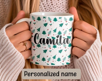 May include: White ceramic mug with a Christmas tree pattern and the name "Camila" in black script. The mug is decorated with green Christmas trees and red berries. The words "Personalized name" are at the bottom.