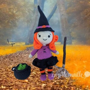 Peut inclure: Une poupée de sorcière en crochet avec des cheveux orange, un chapeau noir et une robe violette. La poupée tient un balai et un chaudron. La poupée est debout dans un décor de forêt avec des feuilles d'automne au sol.