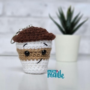 Peut inclure: Un porte-clés tasse de café en crochet avec un couvercle marron foncé, une section supérieure blanche, une bande centrale beige et une base blanche. La tasse a deux yeux en plastique noir et une bouche noire brodée. Un anneau métallique est fixé.