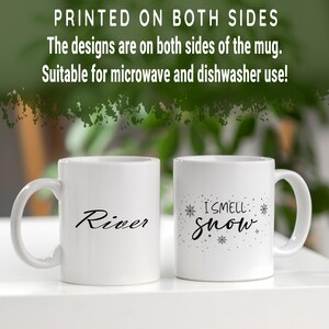 Puede incluir: Dos tazas de cer&aacute;mica blanca con texto negro. Una taza dice "River" y la otra taza dice "I smell snow" con un dise&ntilde;o de copo de nieve.