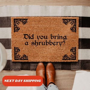 May include: A brown coir doormat with black decorative corners and the text "Did you bring a shrubbery?" printed on it.