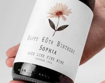 May include: A white wine bottle label with a floral design and the text "Happy 60th Birthday Sophia Aged Like Fine Wine Vintage 1964."